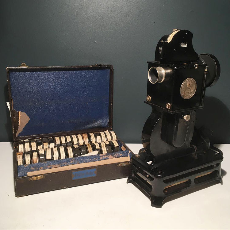 Pathé Baby 9.5mm projector with a case of films in their original cartridges.